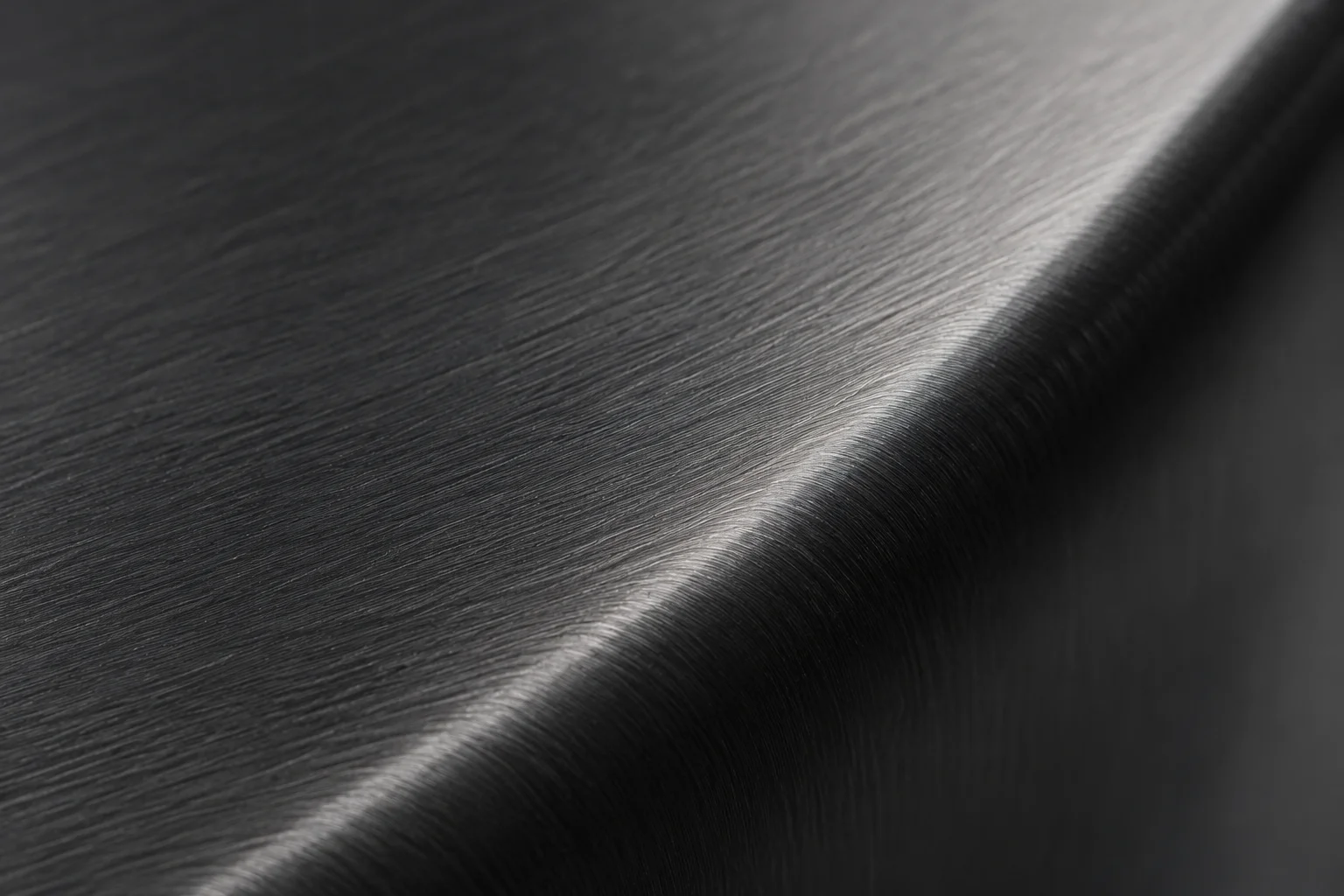 A brushed dark metal surface catching a narrow edge of light.