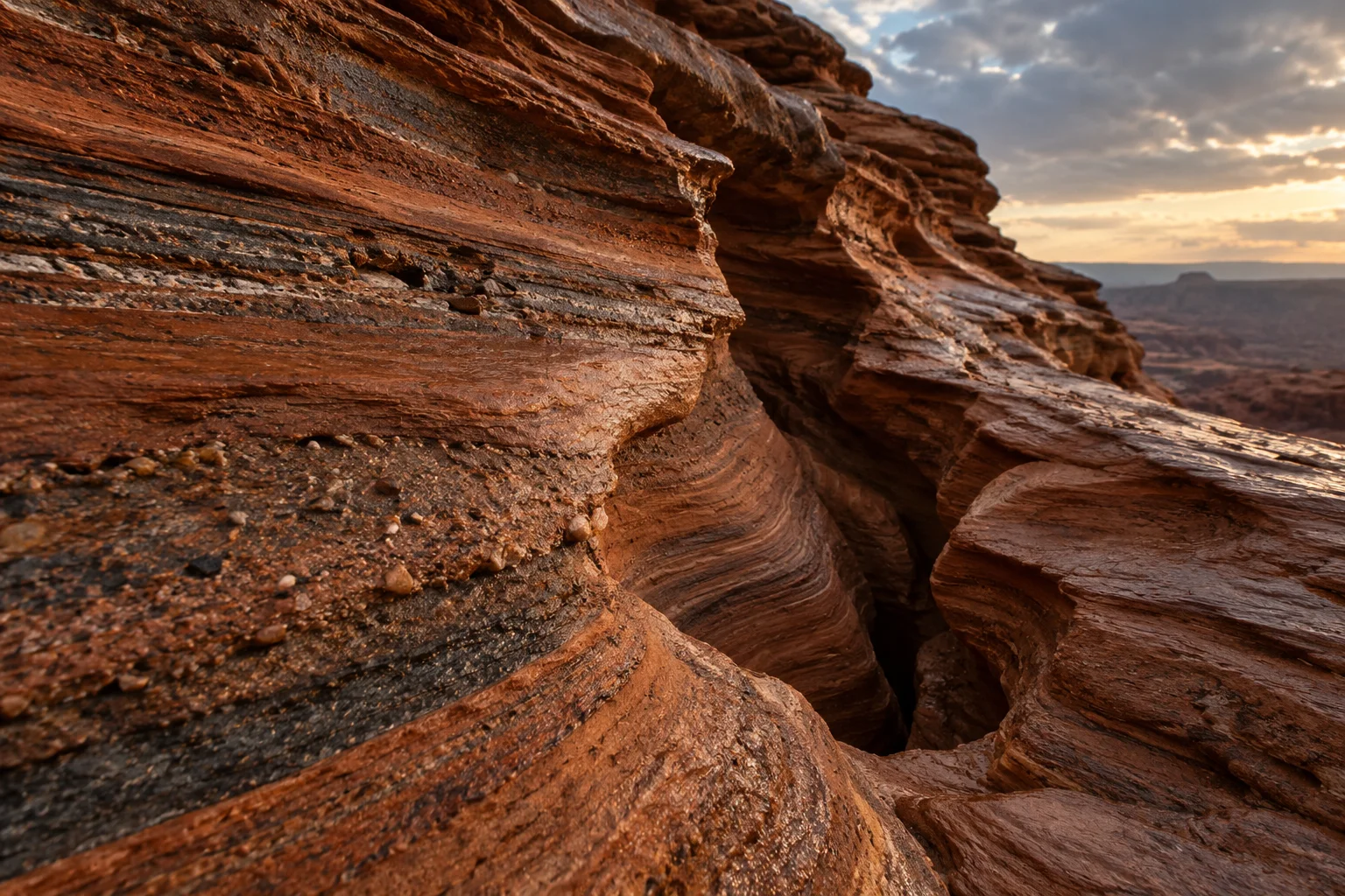 Warm evening light across layered red sandstone and a wide desert horizon.